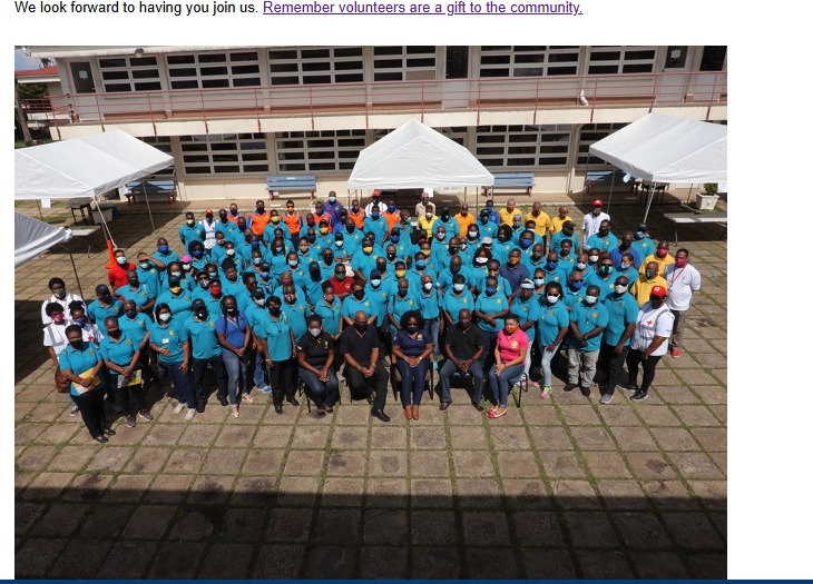 Large group photo of District Emergency Organisation volunteers in matching blue t-shirts assembled outside a Barbados community facility.